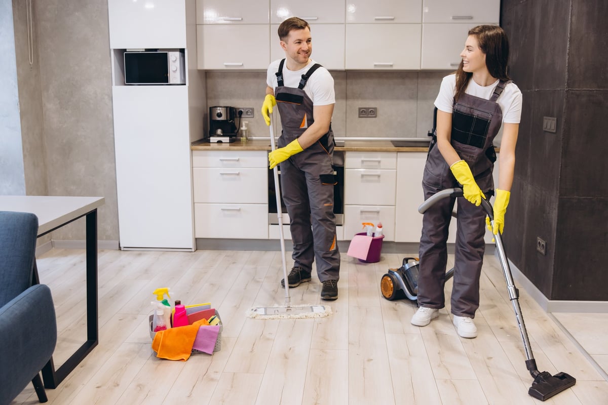 Professional cleaners washing floors and vacuuming a modern apartment