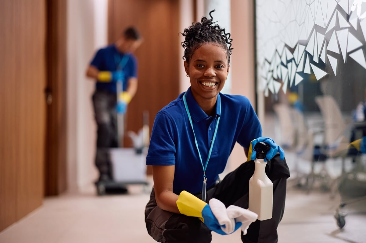 Professional cleaner wiping glass walls in an office building hallway