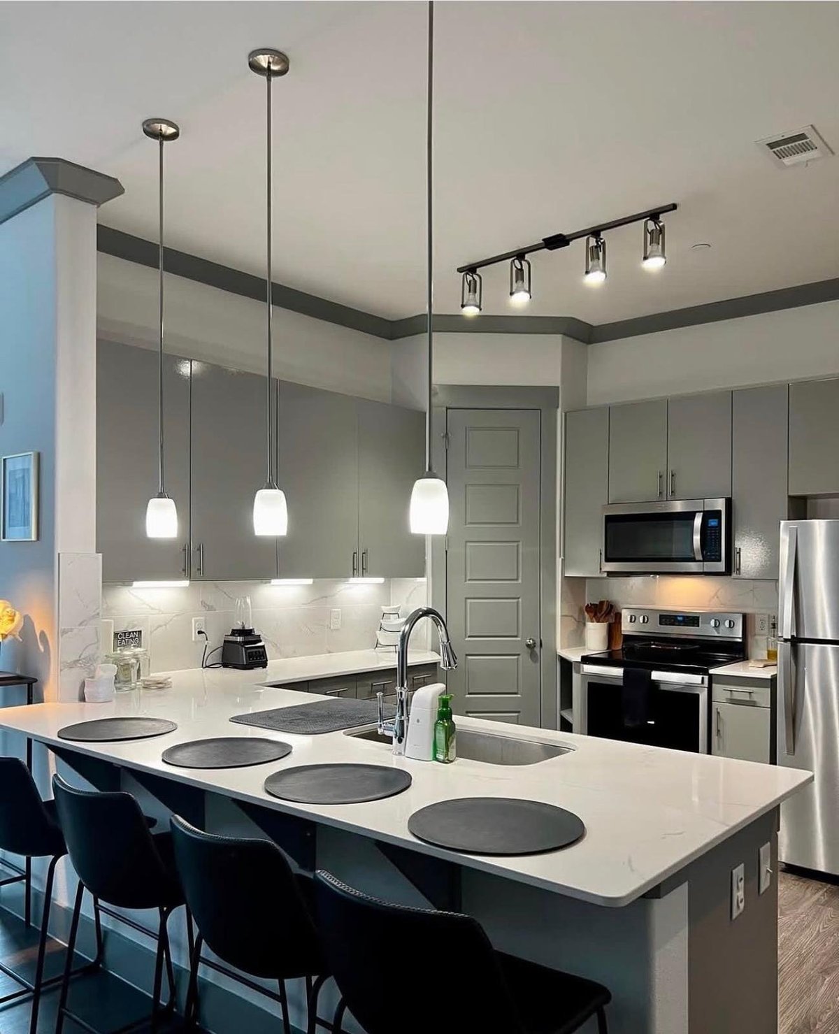 Modern kitchen with white countertops, gray cabinetry, island seating, and stainless steel appliances